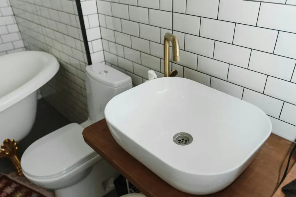Interior kamar mandi modern dengan wastafel keramik dan perlengkapan kloset